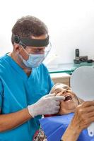 masculino medio -Envejecido dentista a su oficina con un mayor mujer paciente foto