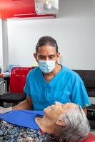 Male middle -aged dentist at his office with a senior woman patient photo