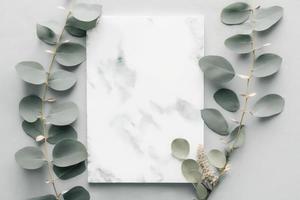 mármol papel blanco, eucalipto ramas en pastel gris fondo, generar ai foto