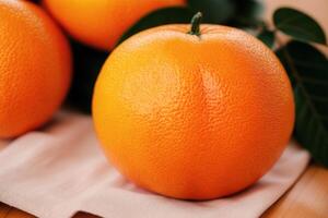 Ripe orange fruit with leaves on wooden table, closeup view. photo