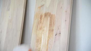 Mens is schilderij plank hout beschermend huid vloeistof, klusjesman met penseel vernieuwing huishouden meubilair hardhout bescherming baan werken concept video