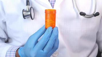 Doctors hand in gloves holding pill container with copy space video