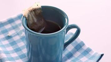 Cup of tea with tea bag on wooden table close-up video