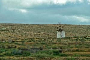 empty mysterious mountainous landscape from the center of the Canary Island Spanish Fuerteventura with a cloudy sky and original windmills photo