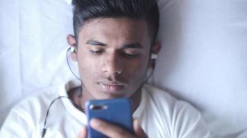 Jeune homme sur lit en utilisant intelligent téléphone , Haut vers le bas video