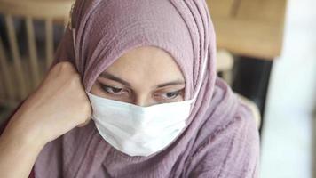 pensativo musulmán mujer con gripe máscara al aire libre , video