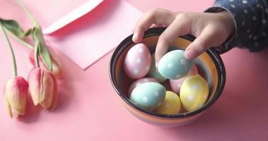 Easter concept with child hand pick colorful egg on pink background video