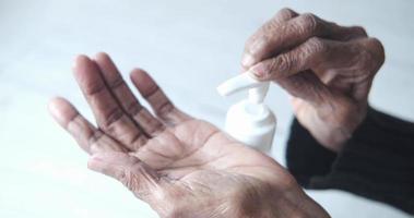 vicino su di anziano donna mano utilizzando disinfettante gel per prevenire virus video