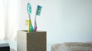 Brosses à dents colorées dans une tasse blanche contre un mur video