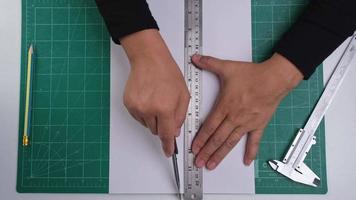 Close-up hands of female cutting paper using utility knife cutter. Female hand with knife cutting paper by ruler on cutting mat. video