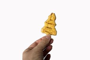 sweet cakes with sugar and cinnamon in the shape of a Christmas tree on a white isolated background kept in hand photo