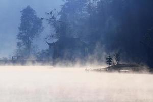 hermosa paisaje cielo de niebla y niebla terminado el lago y amanecer brillante con azul cielo reflexión en el agua superficie a colina tribu pueblo en montaña en Tailandia foto