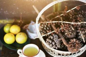 Orange juice with Hot tea cup and Pine cones in basket in beautiful sunlight. Still life photo