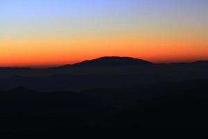 Sunset in sky and cloud, beautiful colorful twilight time with silhouette of mountain. photo