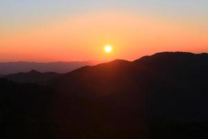 puesta de sol en cielo y nube, hermosa vistoso crepúsculo hora con silueta de montaña. foto