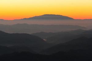 puesta de sol en cielo y nube, hermosa vistoso crepúsculo hora con silueta de montaña. foto