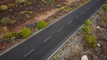 aéreo ver de el mujer carreras a lo largo el abandonado asfalto la carretera a atardecer, espalda vista. montañas en el antecedentes video