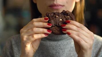 Woman eats a chocolate chip cookies in a cafe video
