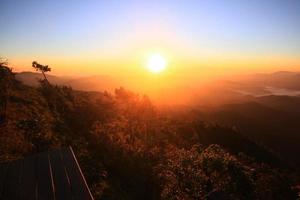 Beautiful golden natural sunlight and twiligh of sunrise shining to in the mist on valley of mountain in Thailand photo