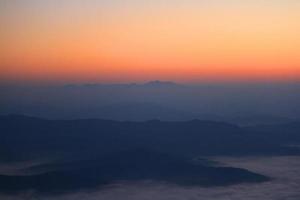 Beautiful golden natural sunlight and twiligh of sunrise shining to in the mist on valley of mountain in Thailand photo