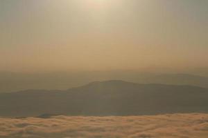 Beautiful golden natural sunlight and twiligh of sunrise shining to in the mist on valley of mountain in Thailand photo