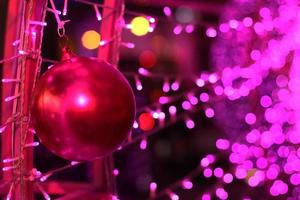 Red ball in Glamour Ultra Violet sparkling and purple glitter bokeh of metallic circle. Multicolored Christmas and New Year glowing light abstract for Christmas and holiday concept. photo