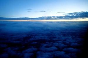 original sunrise landscape over dark clouds seen from the window of an aircraft photo