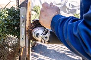 worker cutting old door lock from iron gate photo