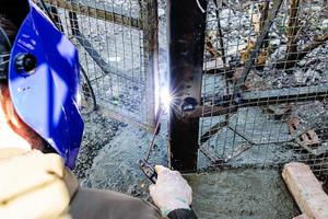 welding door hinge to freshly concreted gate post photo