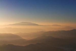 Beautiful Sunset and sunrise on sky and golden twilight time with mist and fog in valley of mountain layer photo