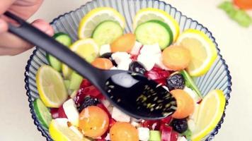 homem fazer salada dentro cozinha, derramando molho e óleo em a salada e preparando isto para comendo, seletivo foco video