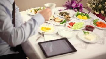 upptagen affärsman på frukost tabell, upptagen affärsman tar vård av hans företag använder sig av läsplatta medan har frukost innan gående till arbete, selektiv fokus video
