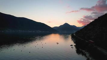 4k aérien métrage de perast un de le célèbre touristique les villes de Monténégro à le coucher du soleil avec coloré des nuages reflétant sur le mer video