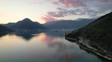 4k aéreo cenas do perast 1 do a famoso turista cidades do Montenegro às pôr do sol com colorida nuvens refletindo em a mar video