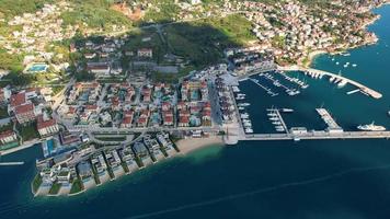 antenn 4k Drönare antal fot av portonovi av montenegro, röd rootops och sten byggnader med Sol ljus och hamn med båtar och ny stad på bakgrund med skön blå hav vatten video