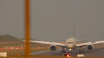 Passenger aircraft arriving, front view through airport fence. Open flaps up, braking. Aviation traffic, airfield. Tourism and travel concept video