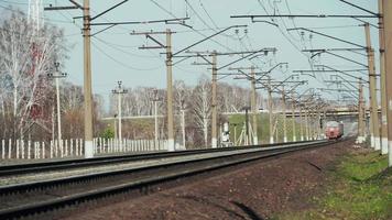 NOVOSIBIRSK, RUSSIA OCTOBER 10, 2021 - Electric train moving on railroad. Electric high speed train passes under car bridge. Passenger train moving under car bridge in autumn day video