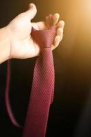 Woman hand holding smart red necktie with natural sunlight photo