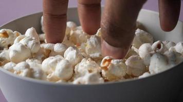dichtbij omhoog van hand- plukken popcorn van een kom video