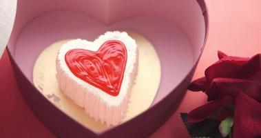 Top view of heart shape cake, gift box, and rose flower on red background video