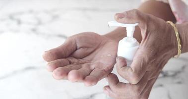 vicino su di anziano donna mano utilizzando disinfettante gel per prevenire virus video