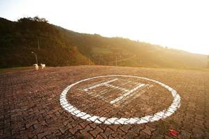 helicóptero aterrizaje símbolo en hormigón piso con natural puesta de sol en el montaña. foto