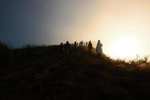 hermosa silueta turista y paisaje Valle de montaña con brumoso y niebla en amanecer brillante en el cielo a phu chee fah colina del Norte de Tailandia foto