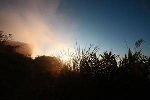 Beautiful silhouette landscape valley of mountain with foggy and mist in winter of sunrise shining on the sky at Phu Chee Fah hill northern of Thailand photo