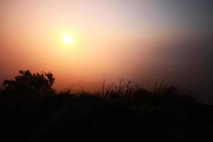 hermosa silueta paisaje Valle de montaña con niebla y niebla en invierno de amanecer brillante en el cielo foto