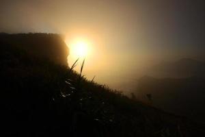 Beautiful silhouette landscape valley of mountain with foggy and mist in winter of sunrise shining on the sky at Phu Chee Fah hill northern of Thailand photo