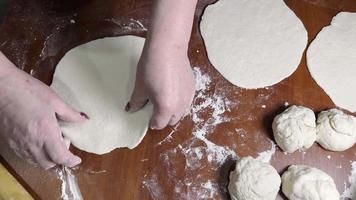 Women's hands are rolling out dough using a rolling pin while making homemade flatbreads. video