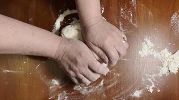 Female hands knead dough on a wooden table. Making homemade bread or pastry. Top view. video