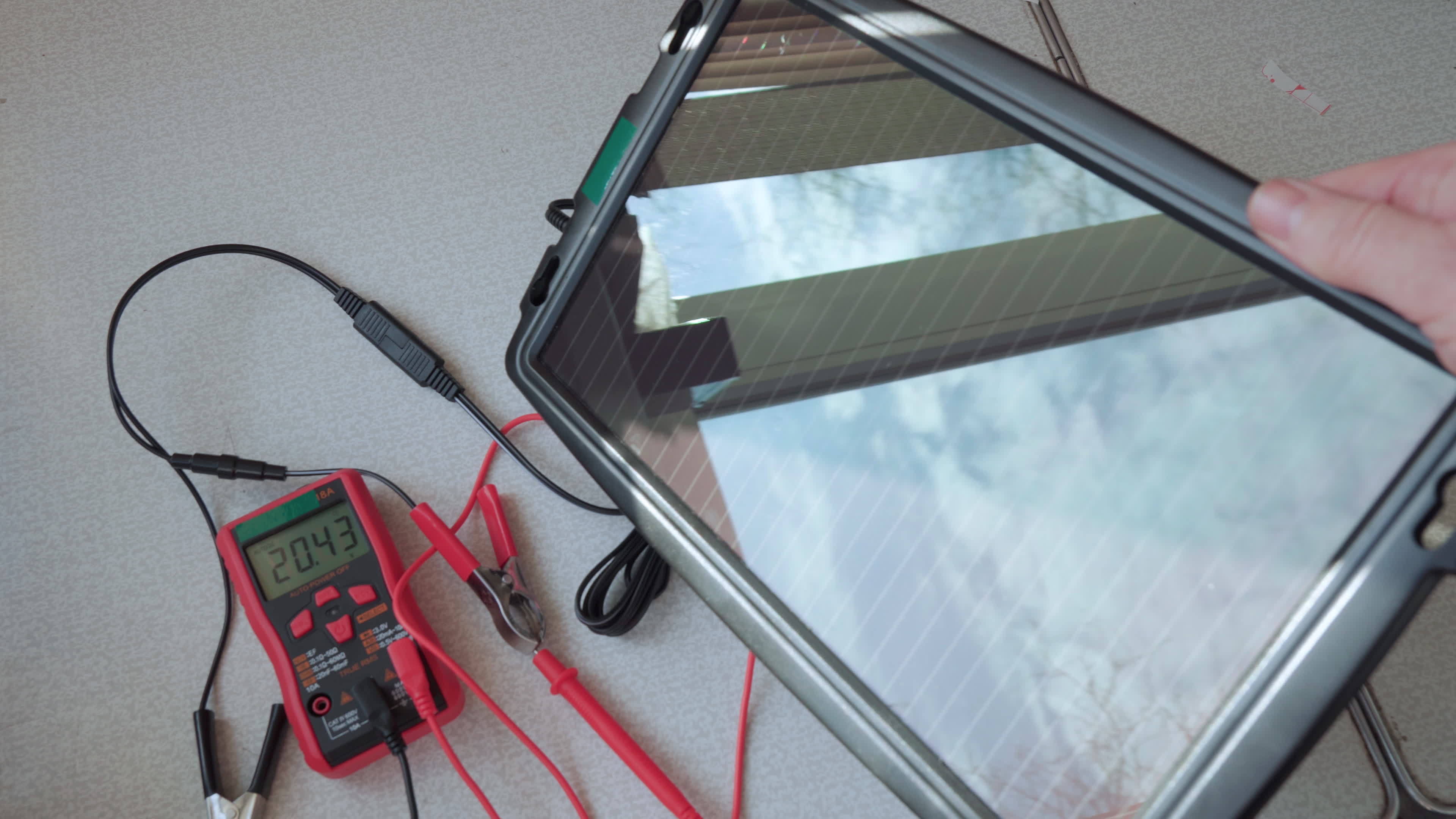 A small solar panel is connected to a tester to measure the output ...