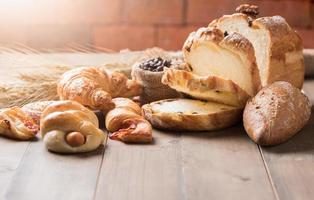 Assortment of baked bread and wheat on wood table photo